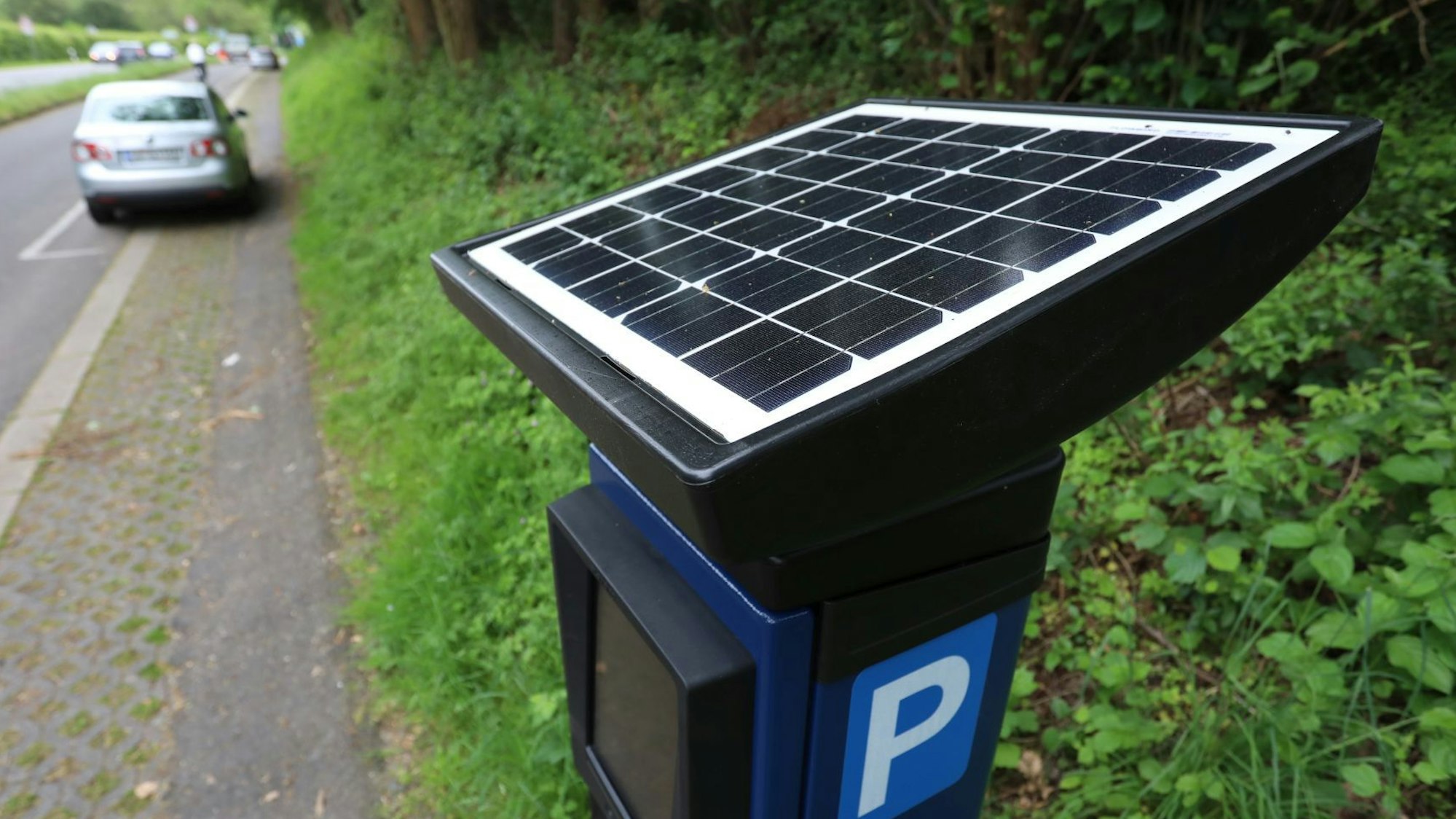 Ein Parkscheinautomat mit Solar-Modul am Rand einer Straße.