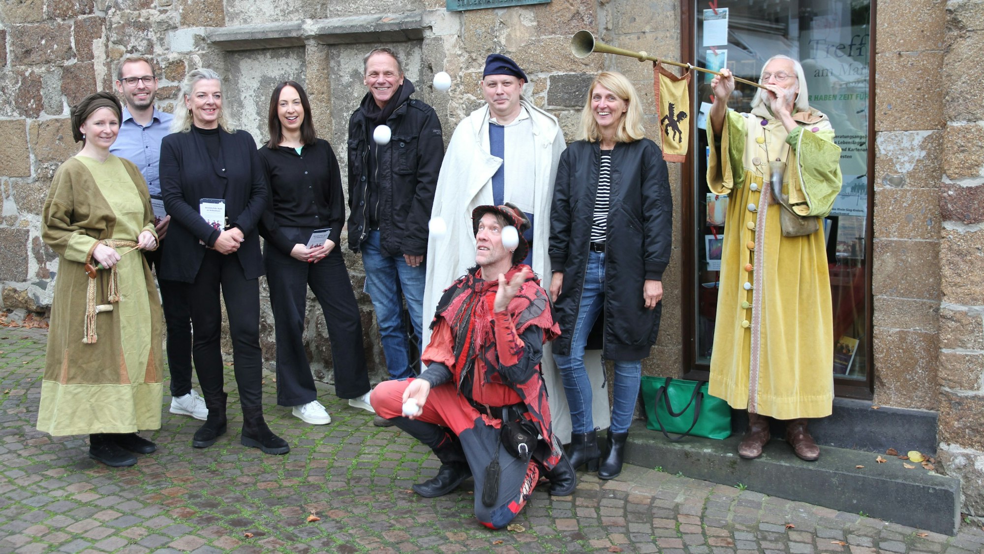 Eine Gruppe vom Menschen, zum Teil in mittelalterlichen Kostümen. Im Vordergrund ein Jongleur mit Bällen.
