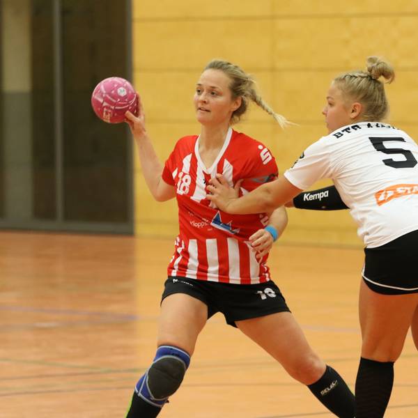 Eine Handballerin spielt einen Pass, eine Gegenspielerin fasst ihr an die Brust.