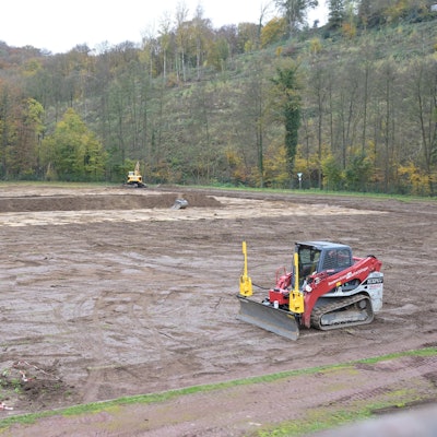 Ein Bagger steht auf einem Sportplatz. Der Rasen wurde vom Fußballfeld entfernt.