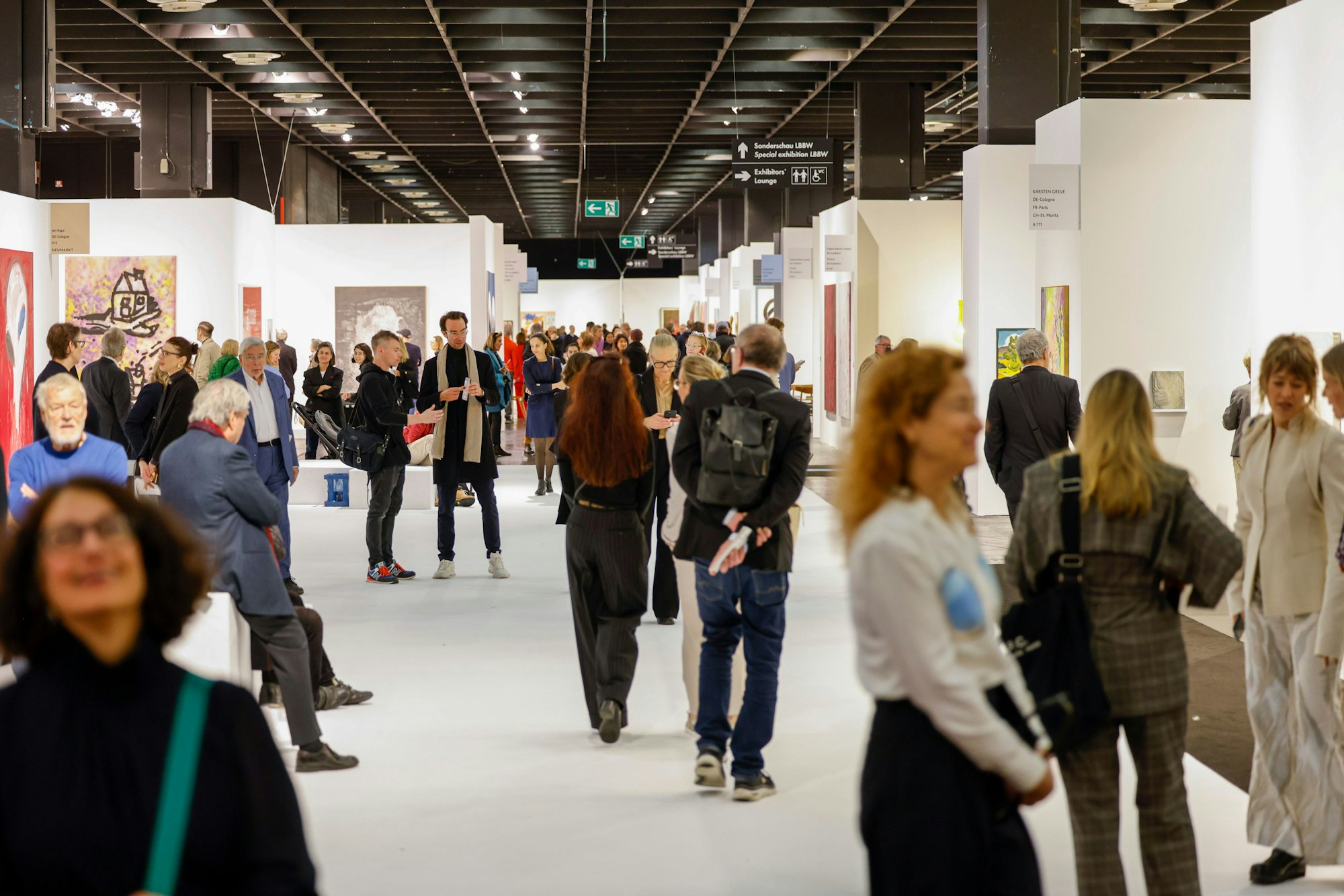 Besucher gehen bei der Eröffnung der Kunstmesse der Art Cologne durch die Hallen.