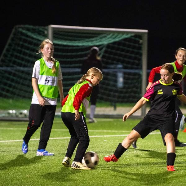 Junge Fußballerinnen trainieren im Flutlicht.