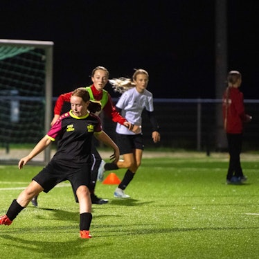 Junge Fußballerinnen trainieren im Flutlicht.