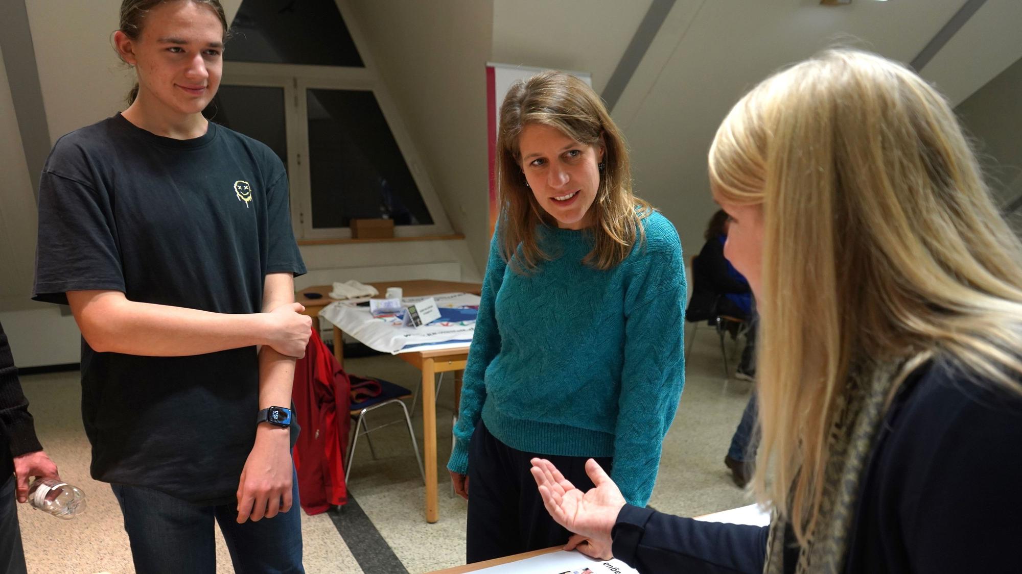 Das Foto zeigt einen Schüler, die Grünen-Landtagsfraktionsvorsitzende Verena Schäffer und eine Lehrerin des Europagymnasiums im Gespräch.