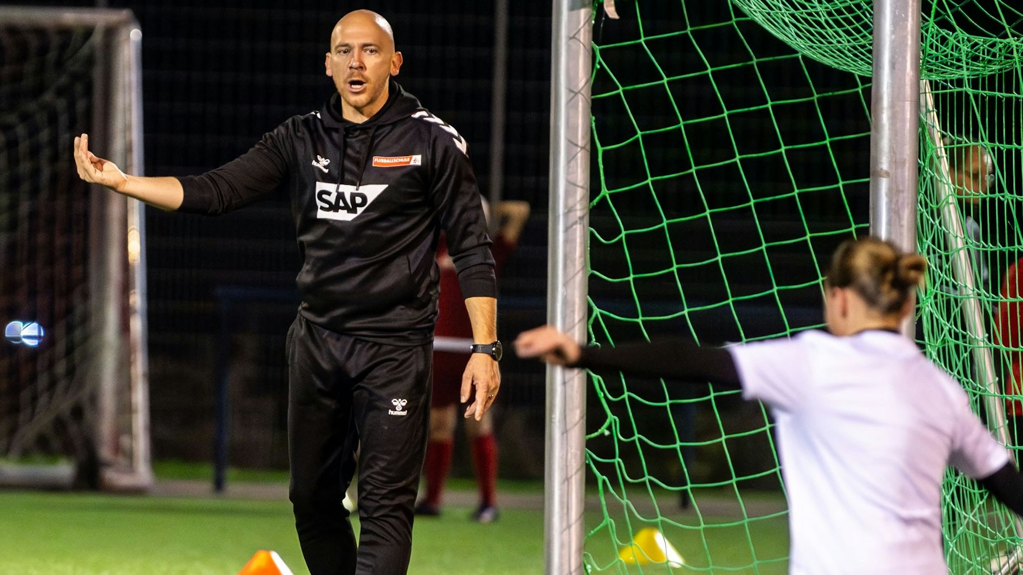 Ein Trainer gibt mit einer Geste eine Anweisung an eine Spielerin.