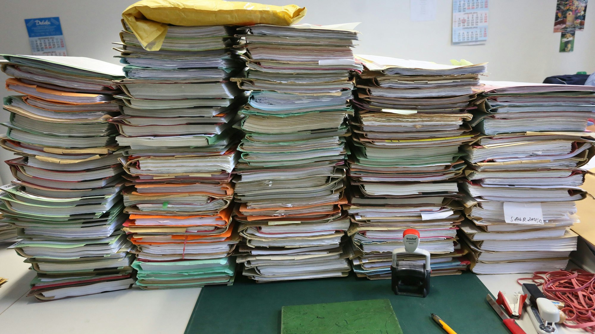 Stapel mit Akten liegen auf einem Schreibtisch.