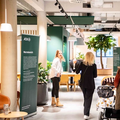 Das Bild zeigt den Eingangsbereich der AOK in Euskirchen. Eine Kundin folgt einer Mitarbeiterin in einen Besprechungsraum.