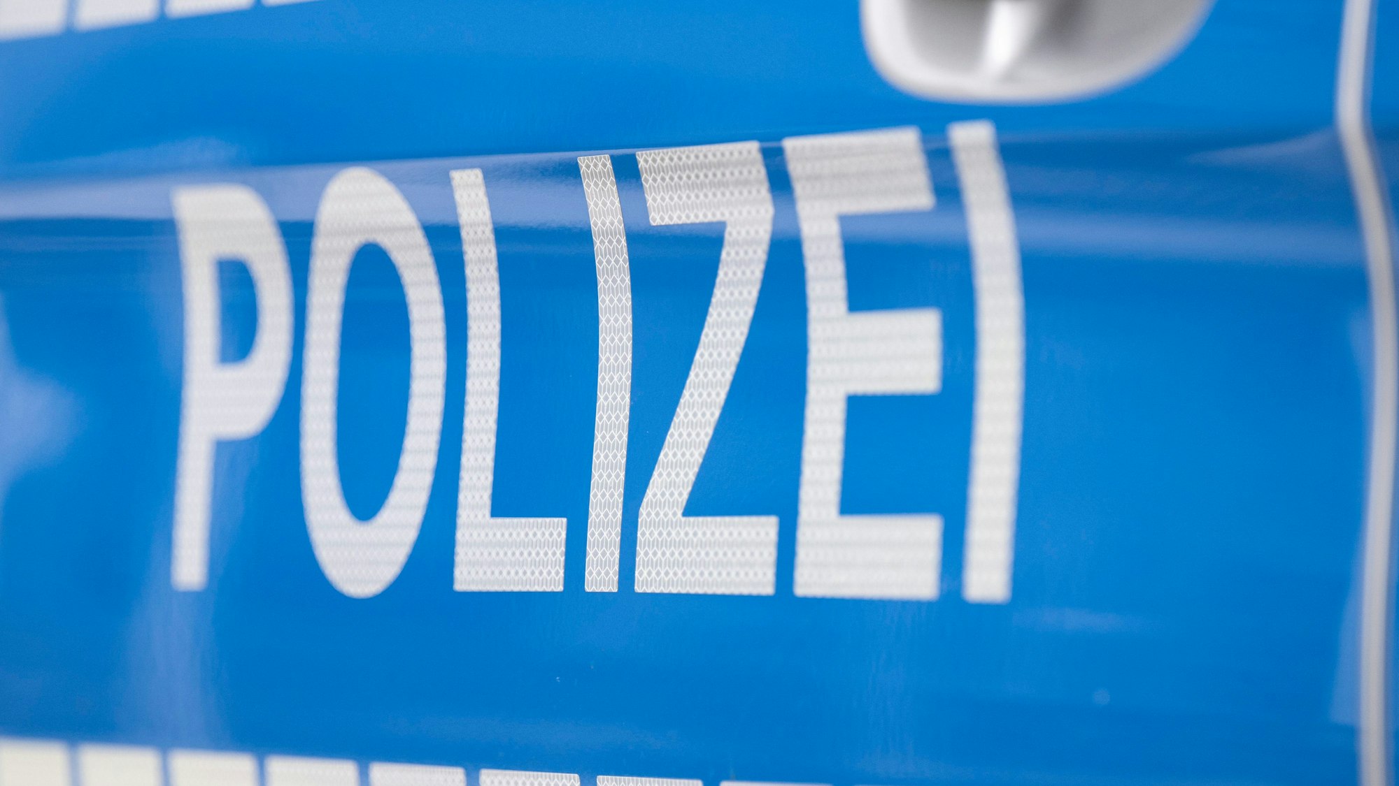 Das Foto zeigt einen Polizei-Schriftzug auf einem Einsatzwagen.