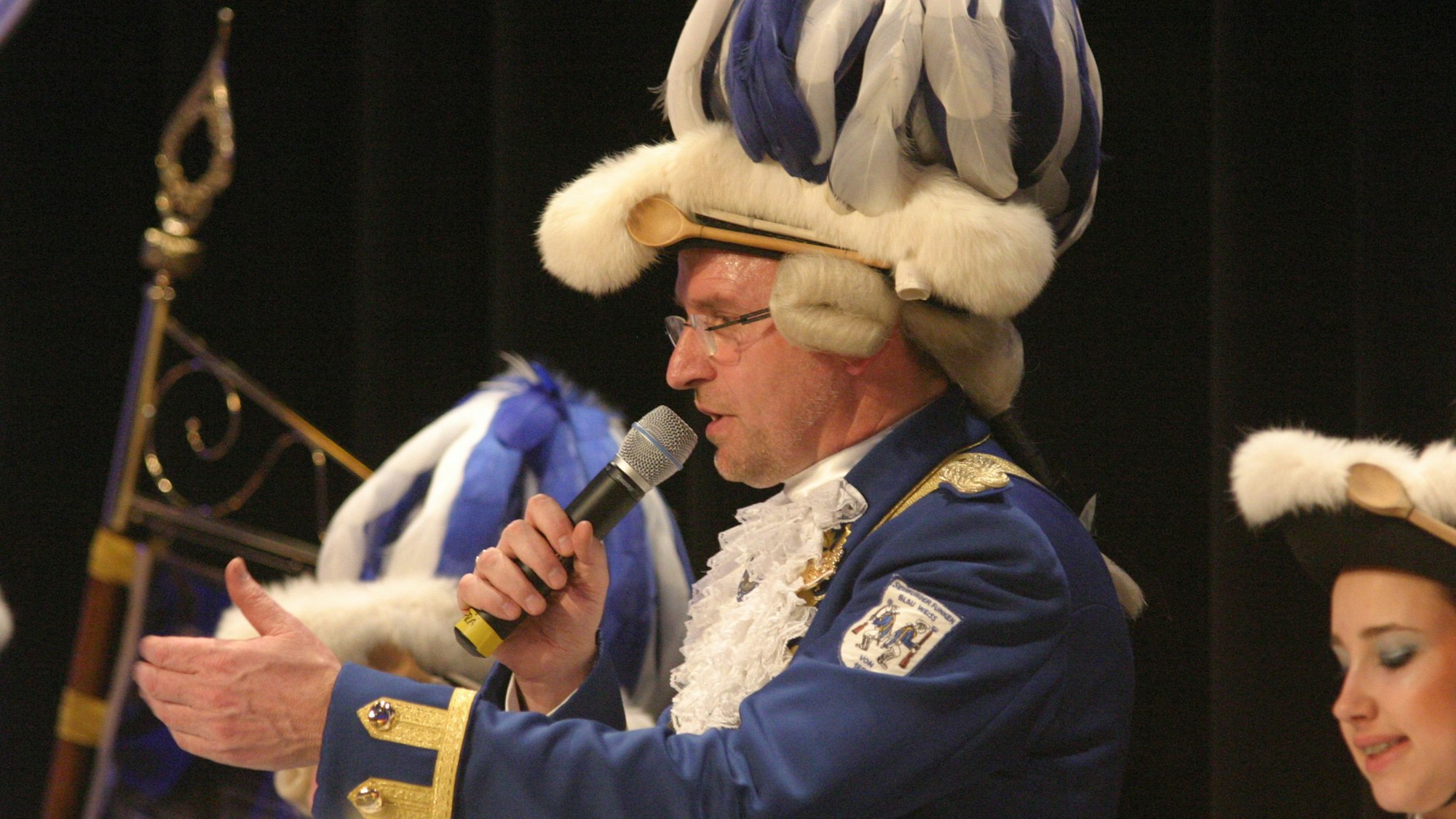 Ein Funke in blau-weißer Uniform mit Mikrofon in der Hand.