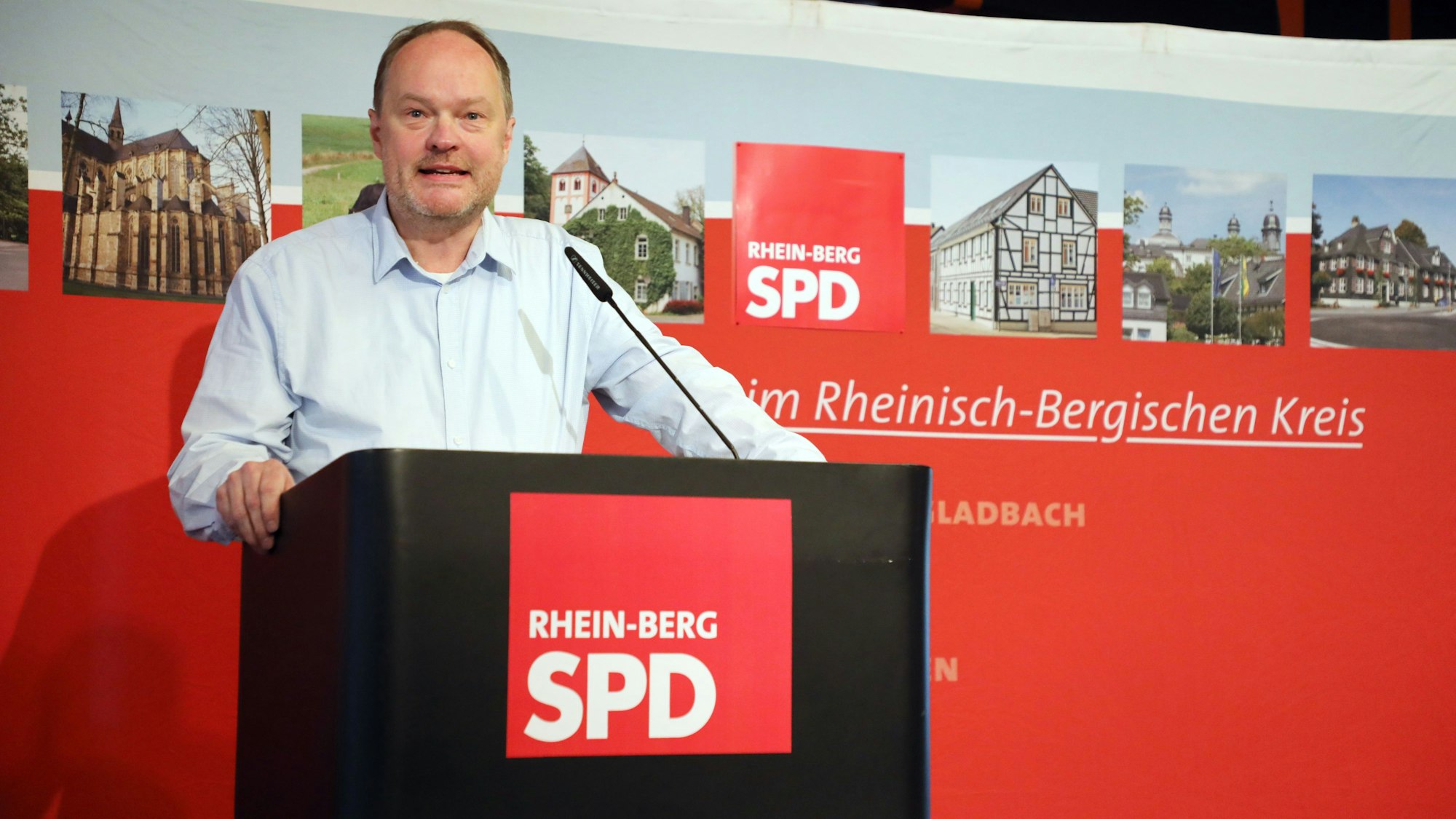 SPD-Kreisvorsitzender Hinrich Schipper steht beim Kreisparteitag der SPD Rhein-Berg Ende September 2024 an einem Rednerpult vor einer SPD-Wand.