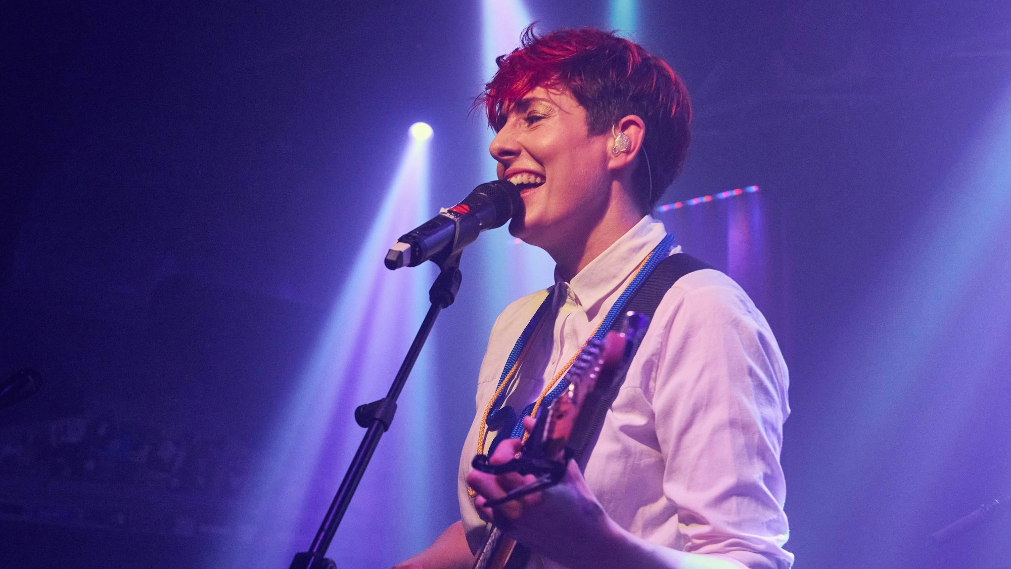 Lisa Spielmann steht mit einer Gitarre vor einem Mikro.