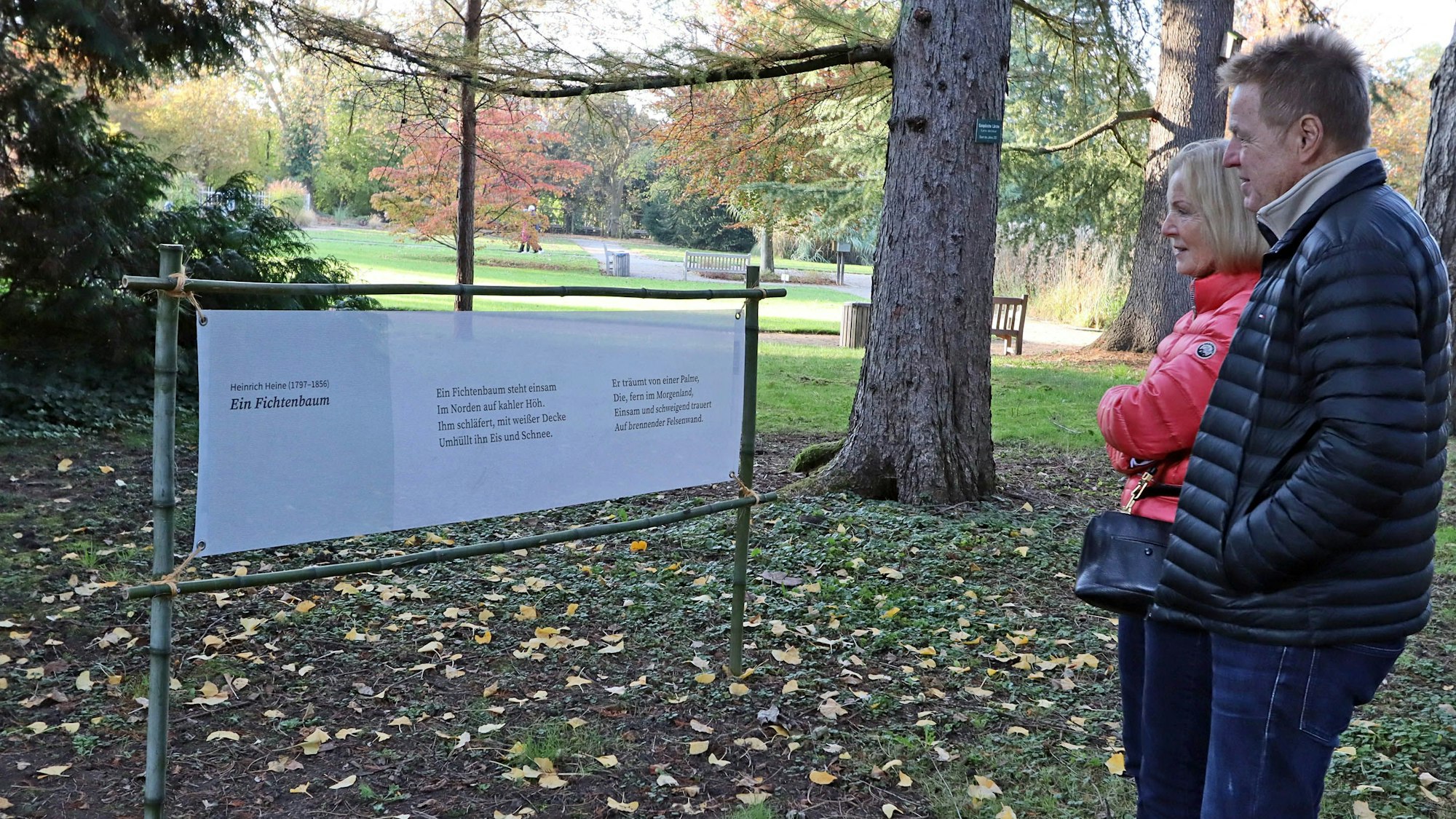 Eine Frau und ein Mann stehen vor einem Gedicht-Aufsteller.