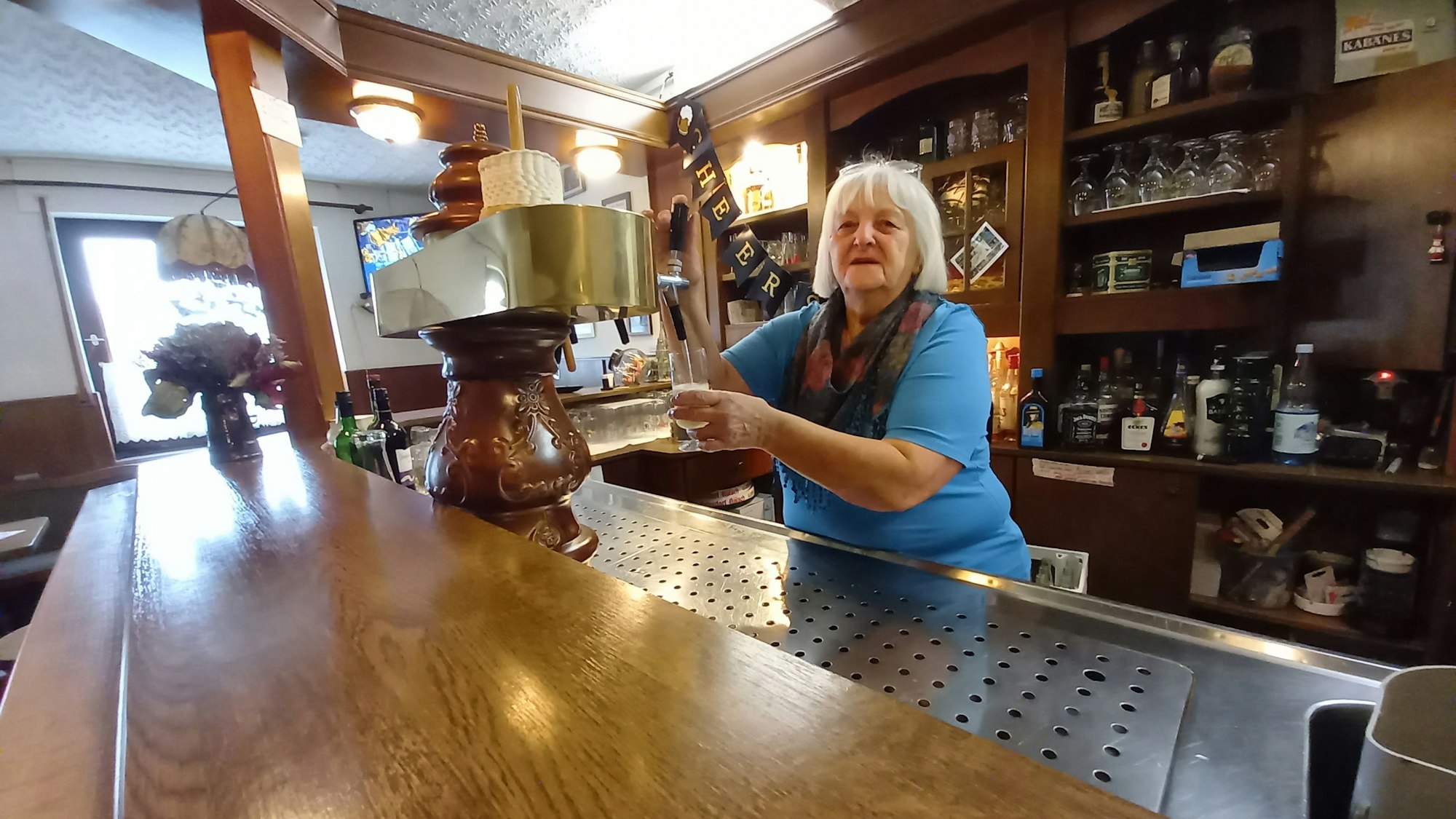 Marita Beuel steht hinter der Theke und zapft ein Bier.