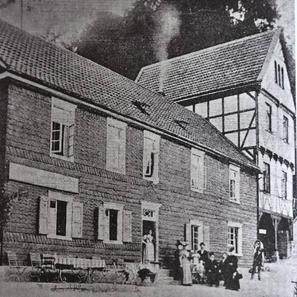 Ein bergisches Lokal, Ende des 19. Jahrhunderts. Davor ein gedeckter Tisch und eine Gruppe von Menschen im Sonntagsstaat