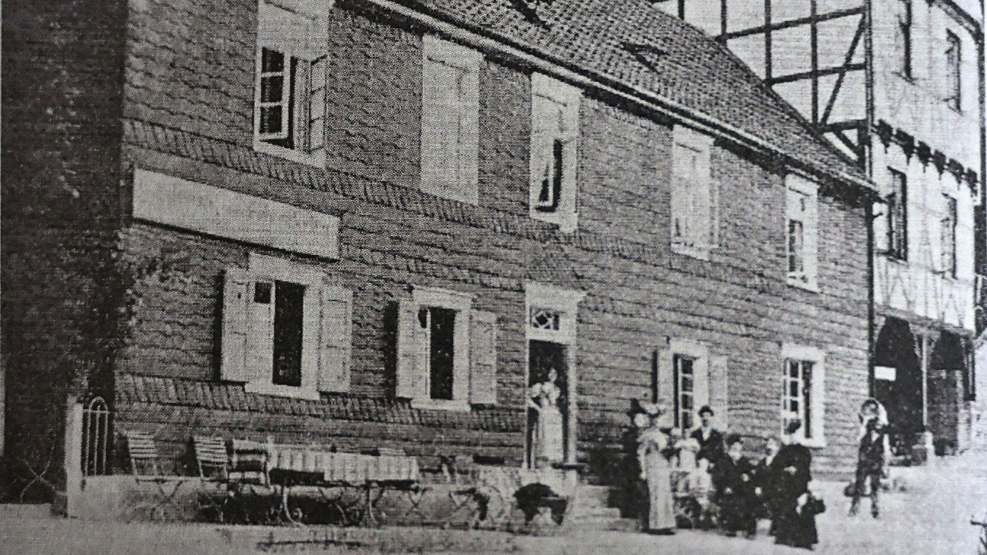 Ein bergisches Lokal, Ende des 19. Jahrhunderts. Davor ein gedeckter Tisch und eine Gruppe von Menschen im Sonntagsstaat