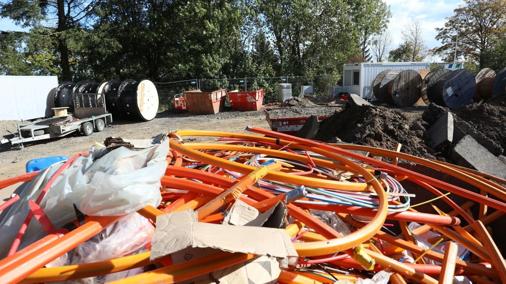 Große rote und orange Kabel liegen übereinander, im Hintergrund stehen Baucontainer