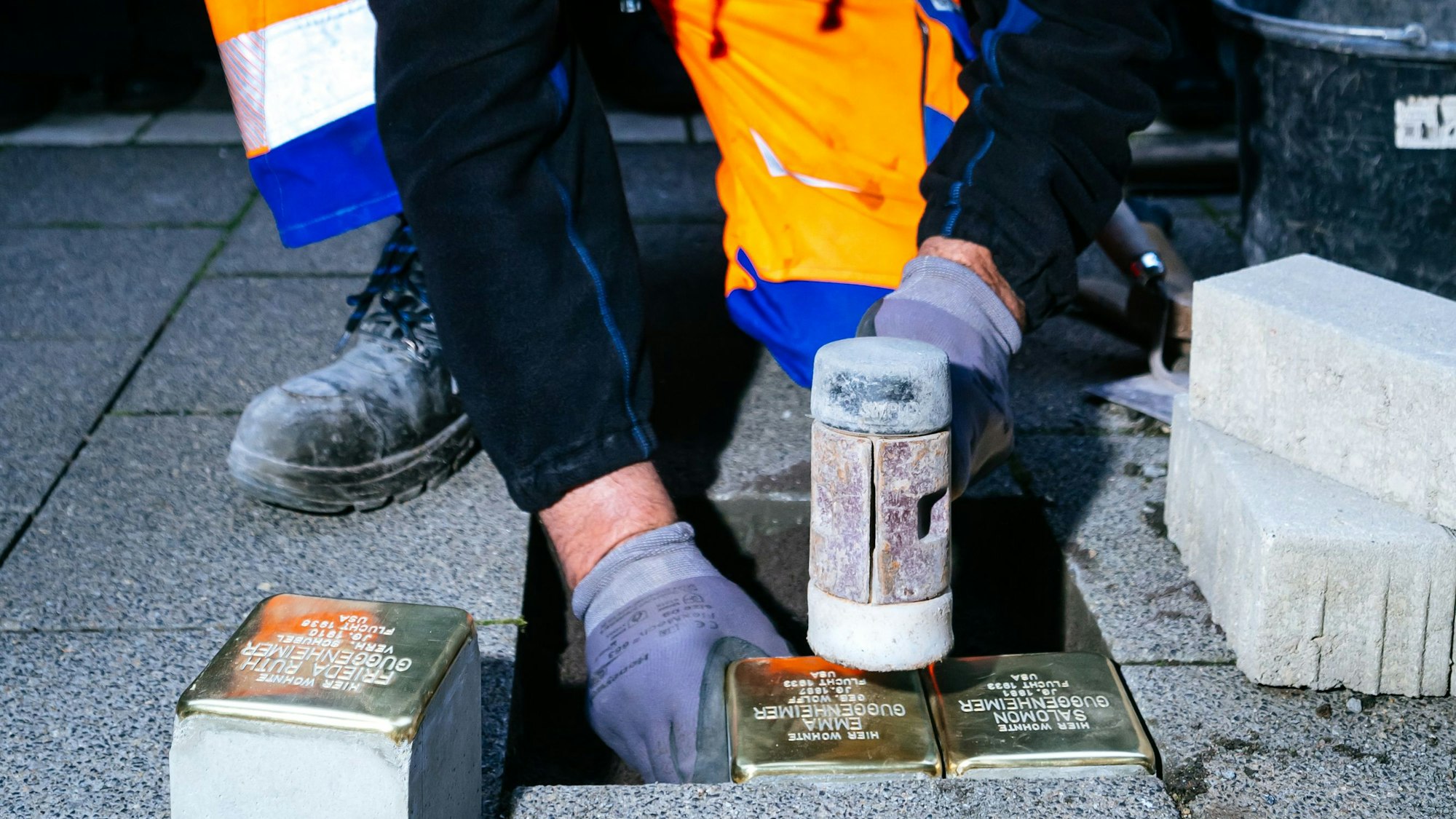 Arbeiter lässt Gedenkstein in den Bürgersteig ein.