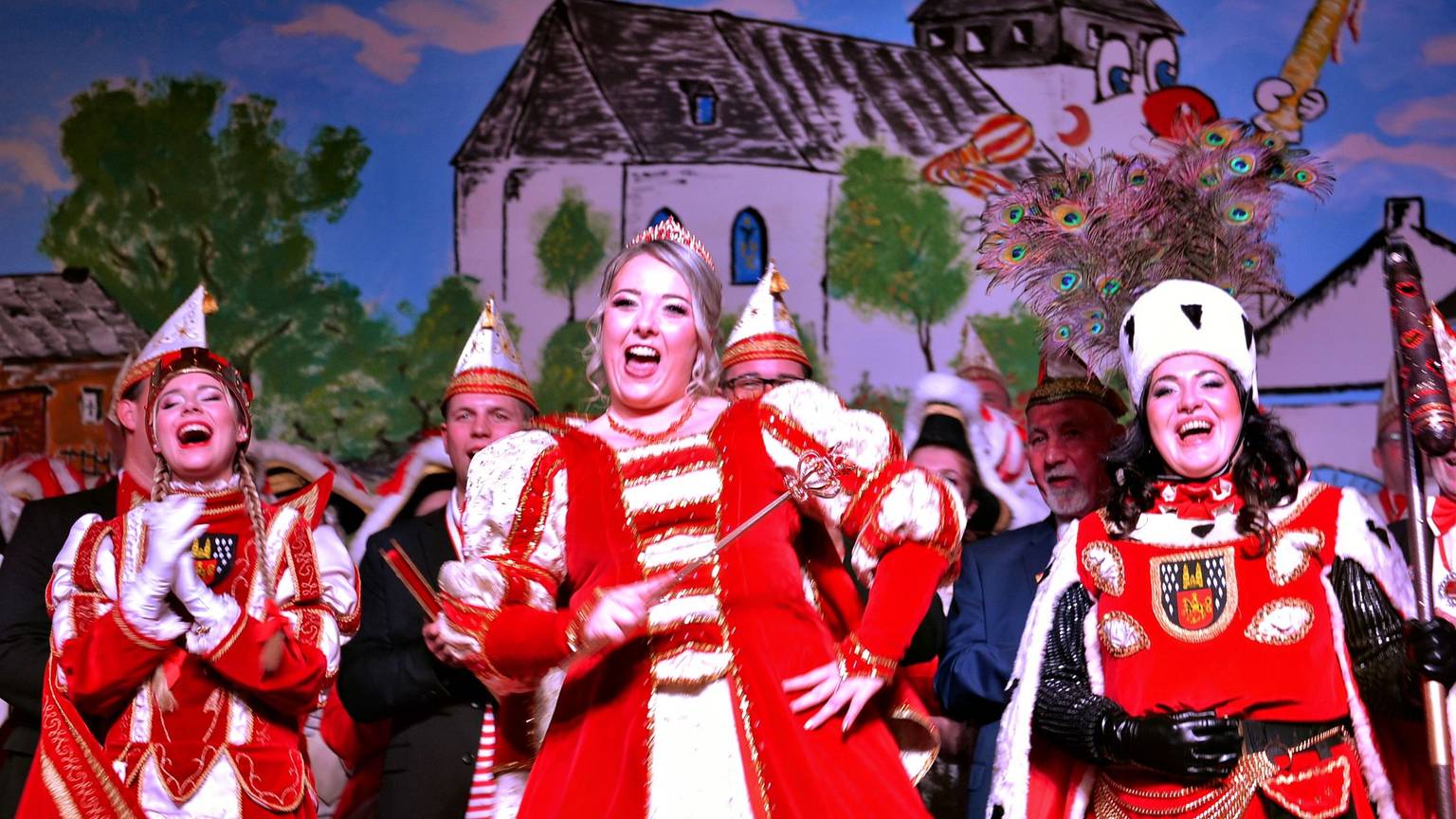 Ein gut gelauntes Damen-Dreigestirn steht lachend und singend auf der Bühne.