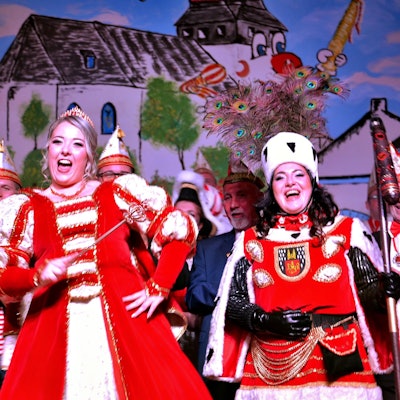 Ein gut gelauntes Damen-Dreigestirn steht lachend und singend auf der Bühne.