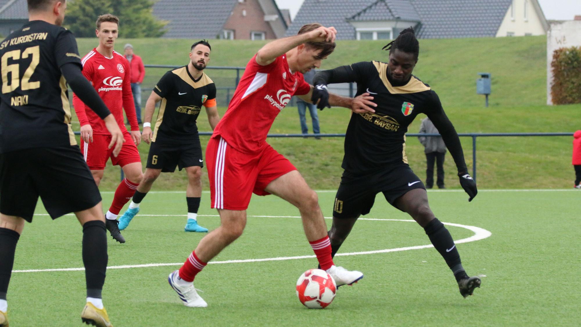 Ein Fußballer behauptet einen Ball vor einem Gegner - und hält diesen auch mit den Händen auf Abstand.