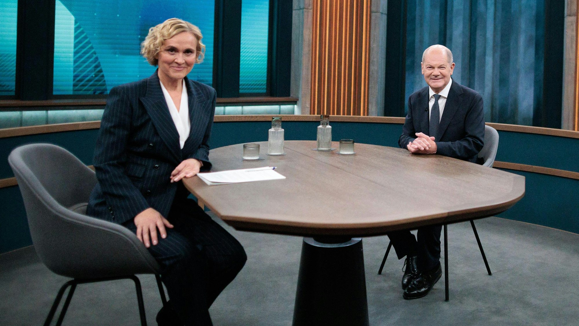 Bundeskanzler Olaf Scholz (SPD) sitzt neben Caren Miosga (l) im Fernsehstudio vor dem Live-Interview der ARD-Sendung «Caren Miosga».