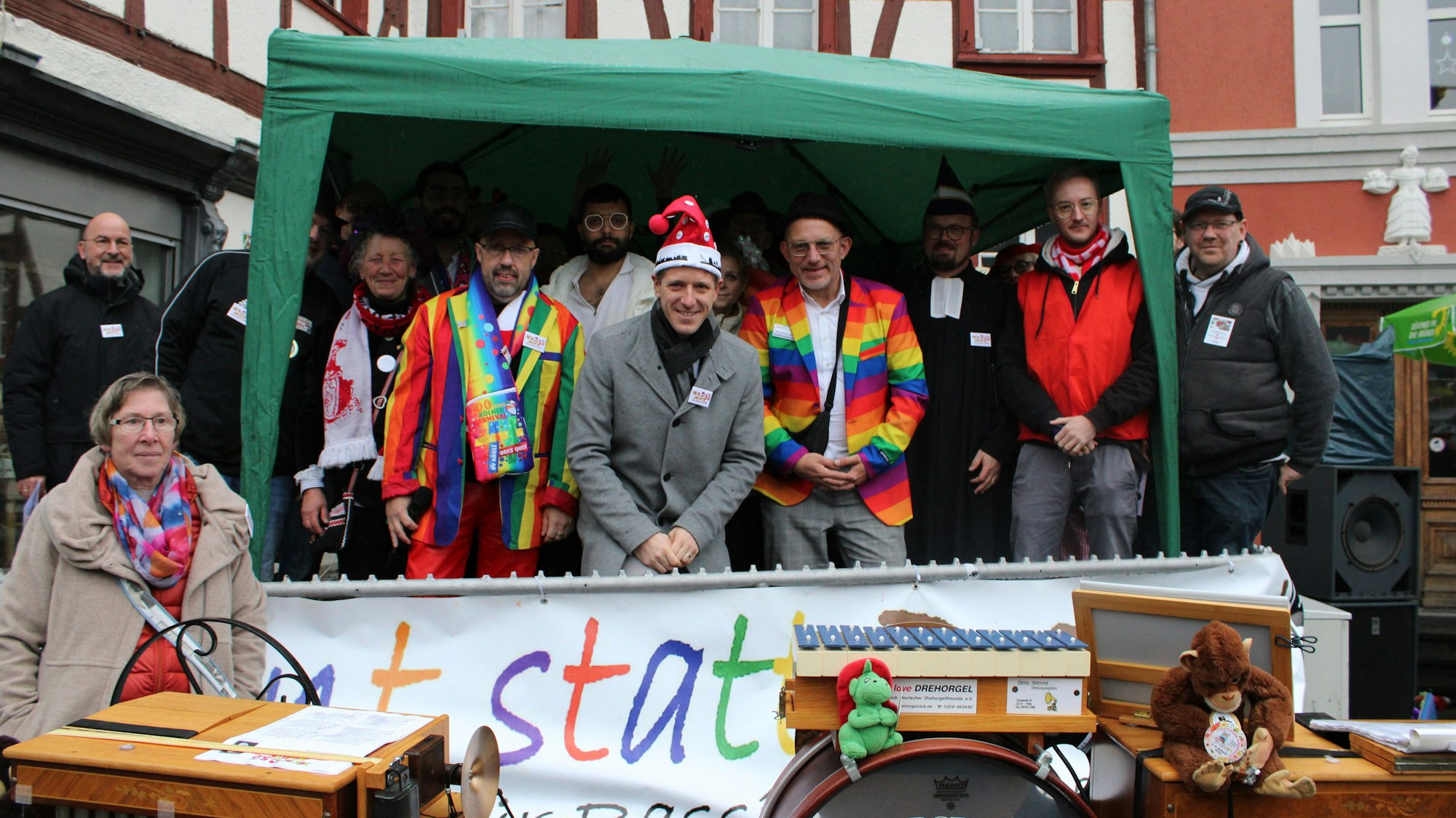 Kostümierte Menschen stehen auf einer Bühne unter einem Zelt.