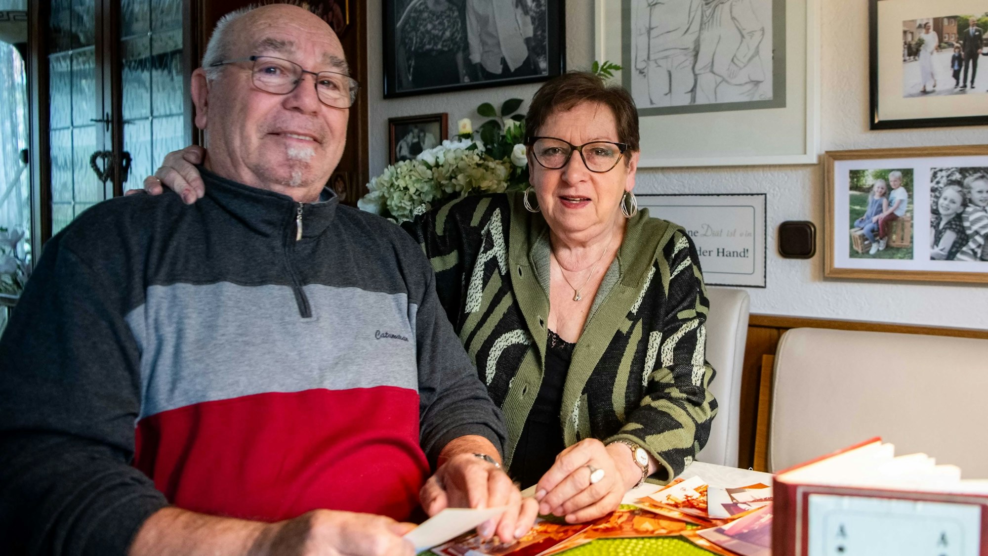 Das Bild zeigt Hans und Christa Klinkenberg am Wohnzimmertisch. Sie hat ihren rechten Arm um ihn gelegt.