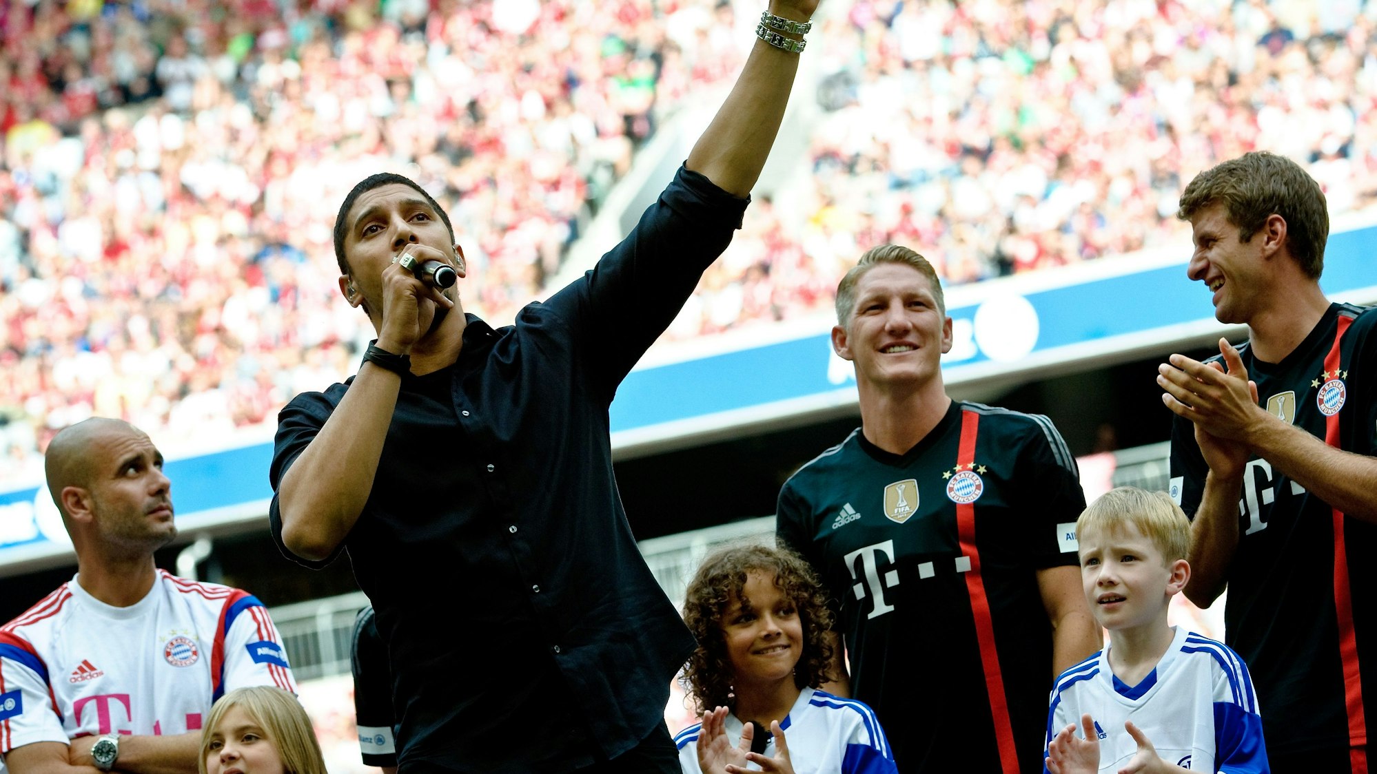 Andreas Bourani (vorne) trat im August 2014 bei der Teampräsentation des Fußball-Bundesligisten FC Bayern München in der Allianz Arena auf. Hinter ihm stehen Bayerns Trainer Pep Guardiola (l-r), Bastian Schweinsteiger und Thomas Müller.