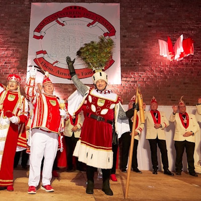Ein männliches Dreigestirn steht winkend auf der Bühne der Turnhalle.