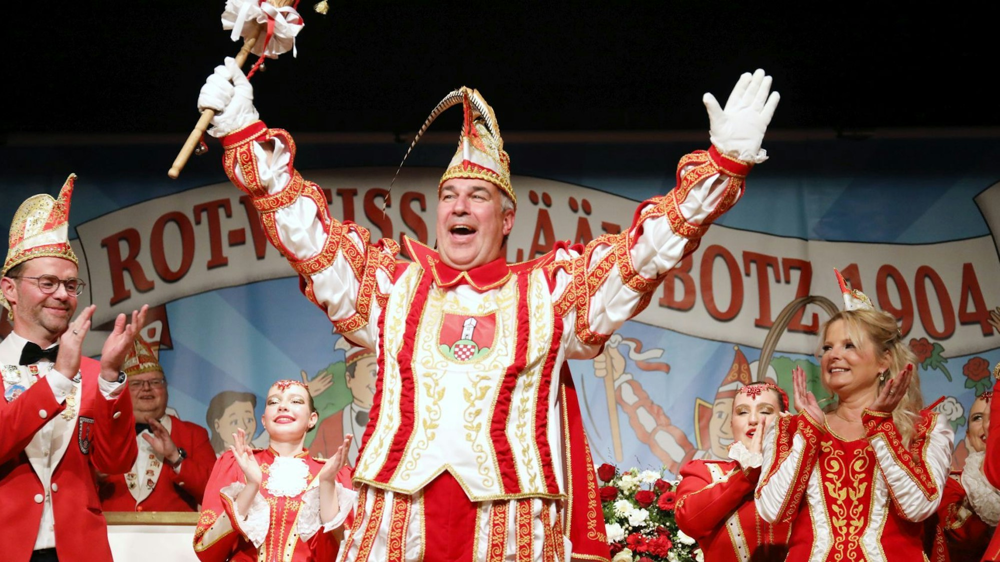 Karnevalisten in rot-weißen Gewändern auf einer Bühne, der Prinz lässt sich feiern.