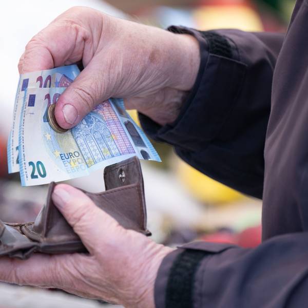 Eine Frau sortiert das Wechselgeld für ihre Einkäufe in ein Portemonnaie.