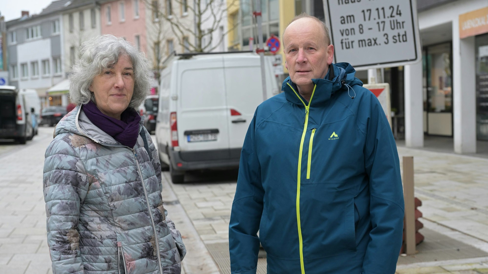 Die Eheleute stehen nebeneinander in der Fußgängerzone.
