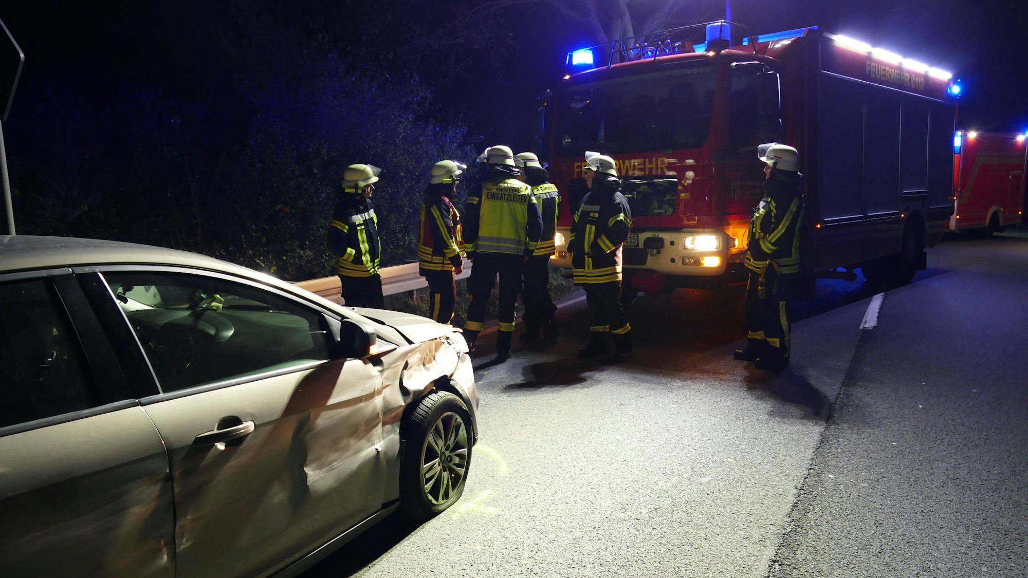 Feuerwehrleute stehen vor dem Auto der Unfallverursacherin.
