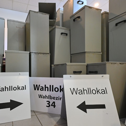 Wahlurnen und -schilder stehen in einem Lager. (Symbolbild)