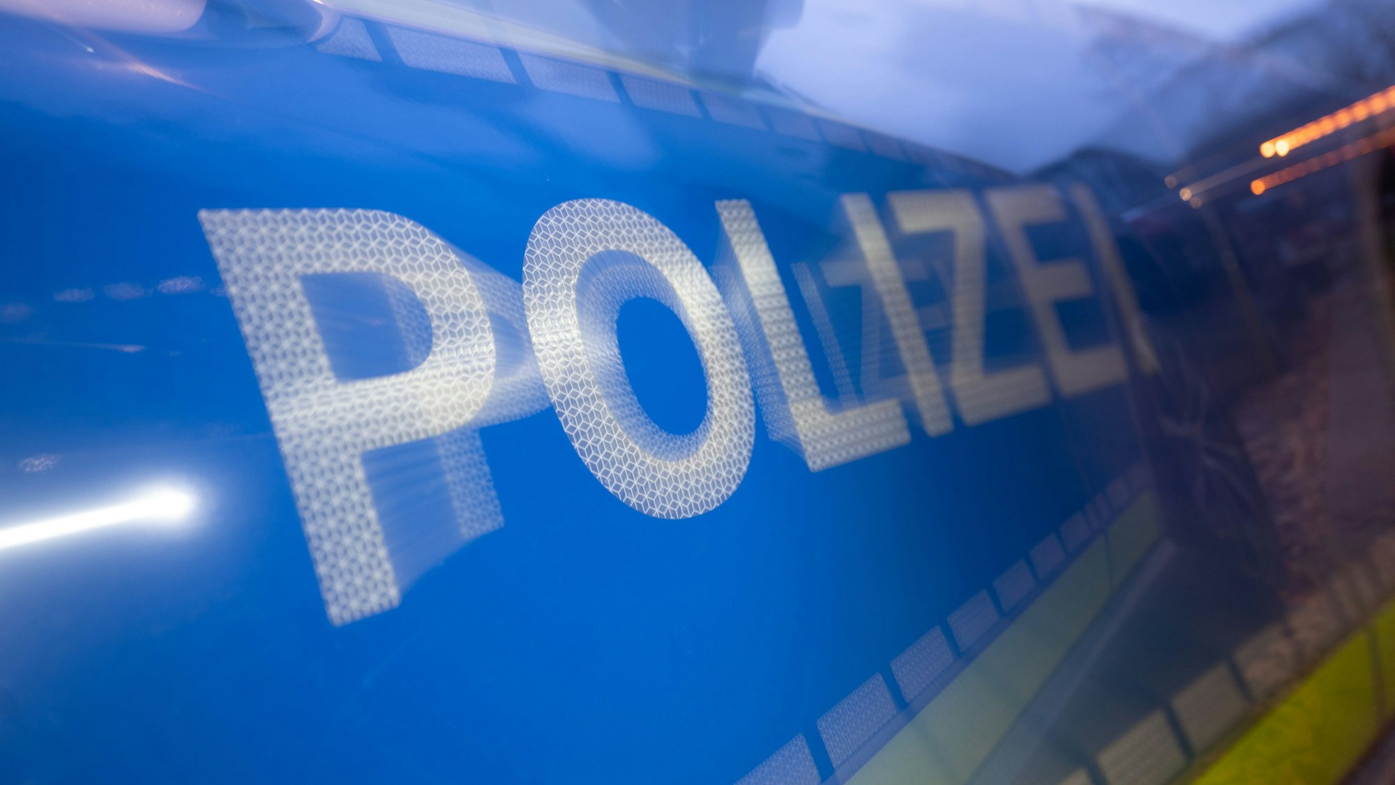 Auf einer Fahrzeugtür steht der Schriftzug Polizei.