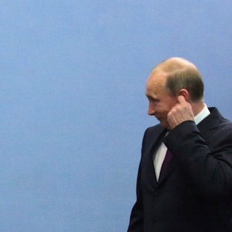 Kremlchef Wladimir Putin neben einer deutschen Fahne. Der russische Präsident schweigt bislang zum Wahlsieg von Friedrich Merz in Deutschland. (Archivbild)