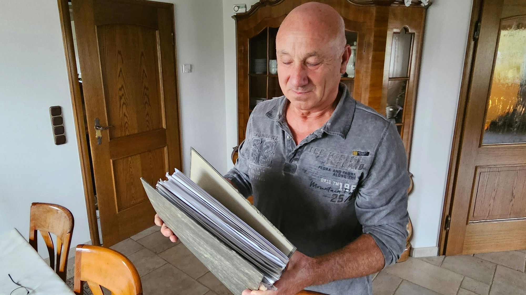 Peter Schildgen hält einen vollen Aktenordner.