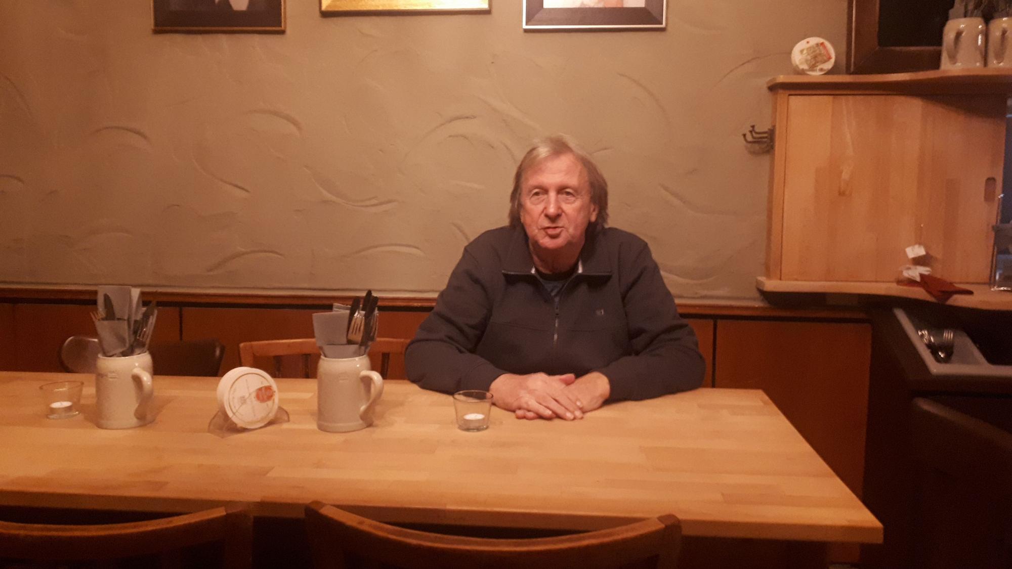 Mann sitzt an einem Tisch in einem Gasthaus.