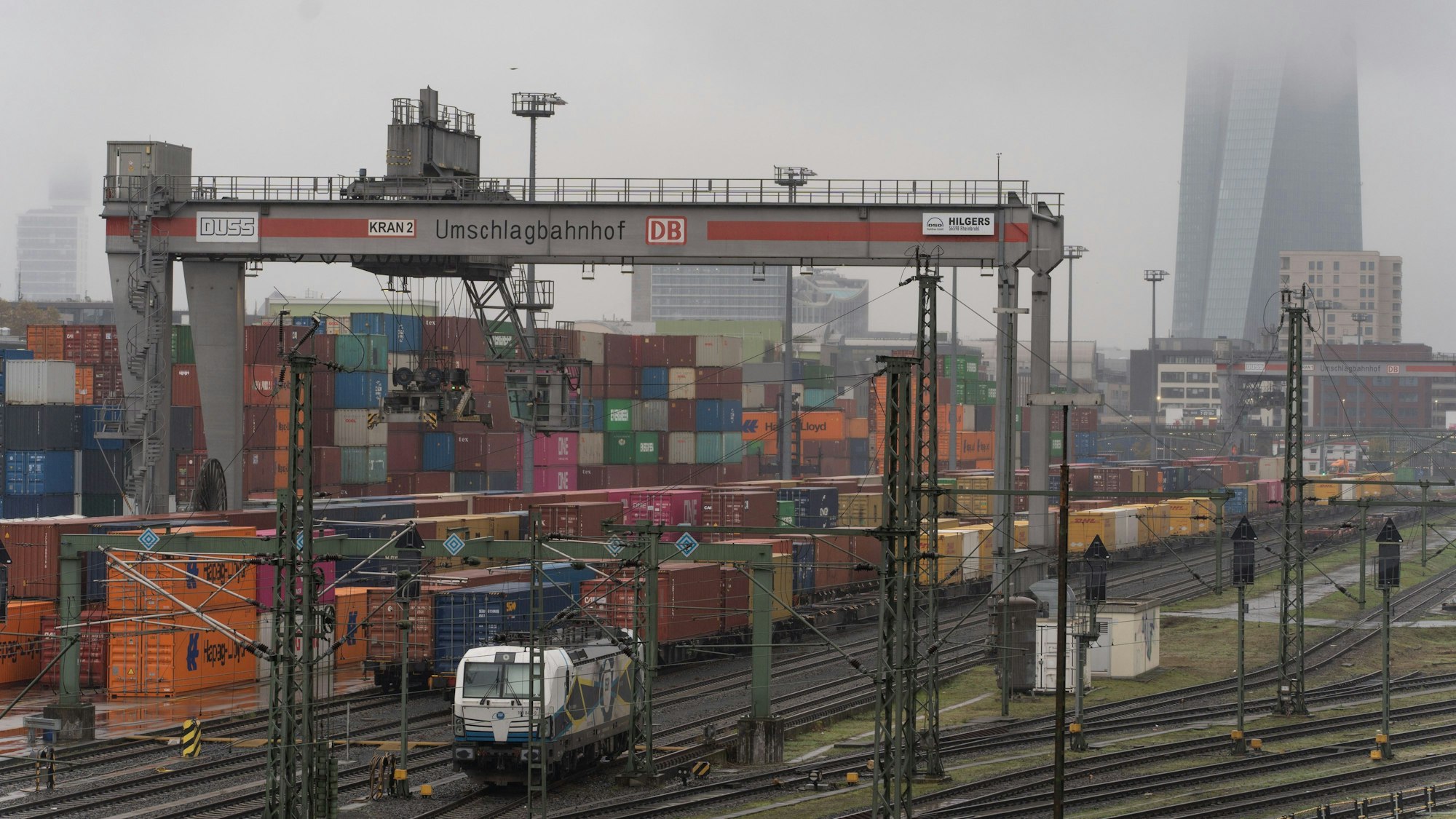 11.11.2024, Hessen, Frankfurt/Main: Die in Hochnebel getauchte Europäische Zentralbank (EZB) überragt das Containerterminal auf dem Güterbahnhof in Frankfurt am Main. Foto: Etienne Dötsch/dpa +++ dpa-Bildfunk +++