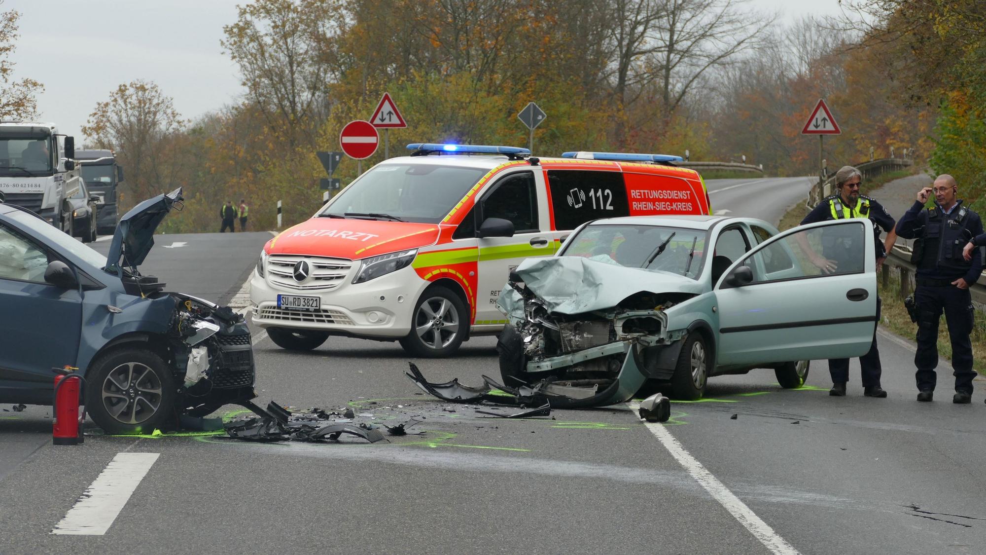 Zwei kaputte Autos stehen auf der Straße, dahinter ein Notarztfahrzeug.