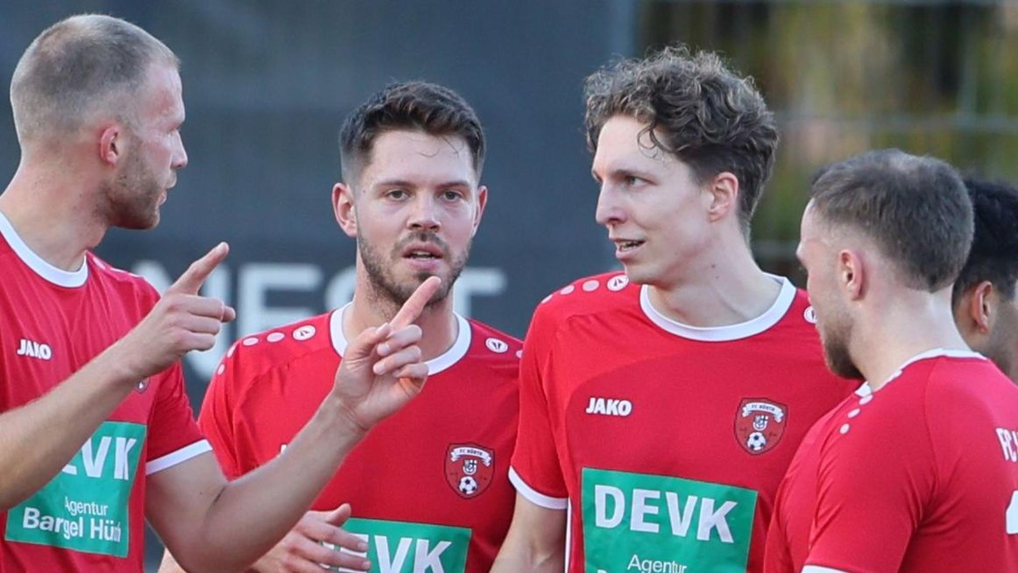 Das Foto zeigt vier Spieler des FC Hürth in roten Trikots, die sich über ein Tor freuen.