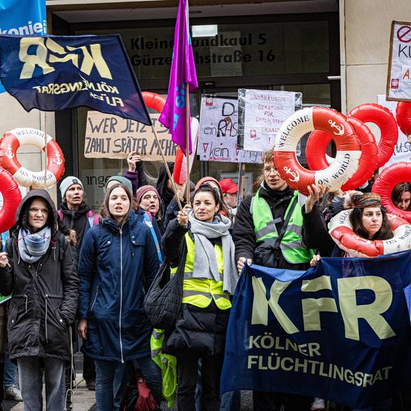Menschen mit Schwimmringen und Plakate demonstrieren.