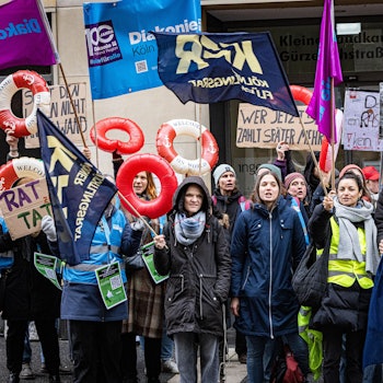 Menschen mit Schwimmringen und Plakate demonstrieren.
