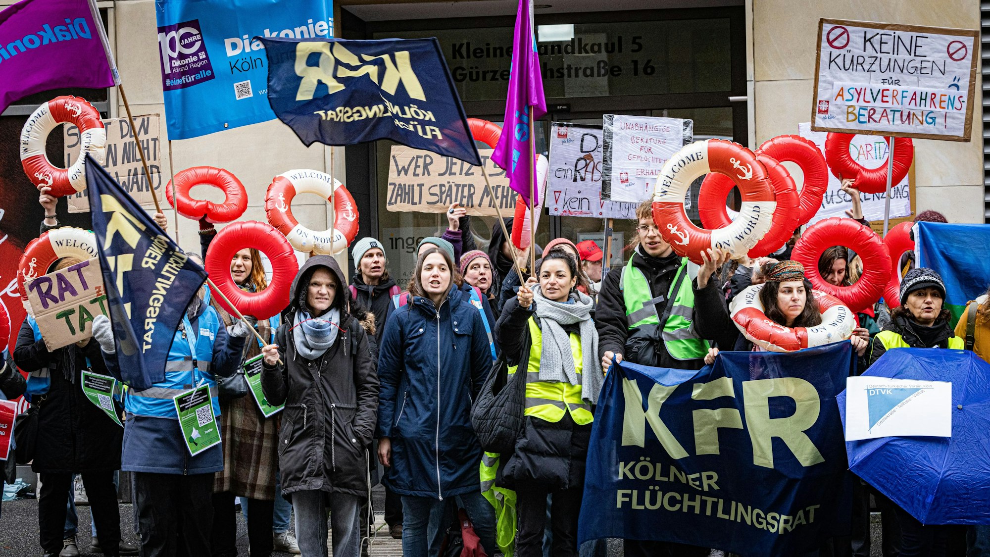 Menschen mit Schwimmringen und Plakate demonstrieren.
