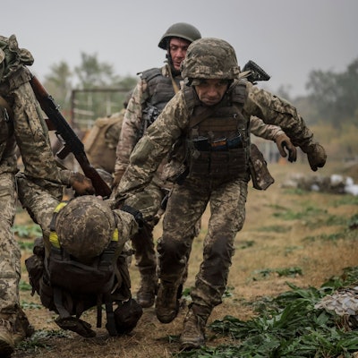 Soldaten tragen einen anderen Soldaten weg.
