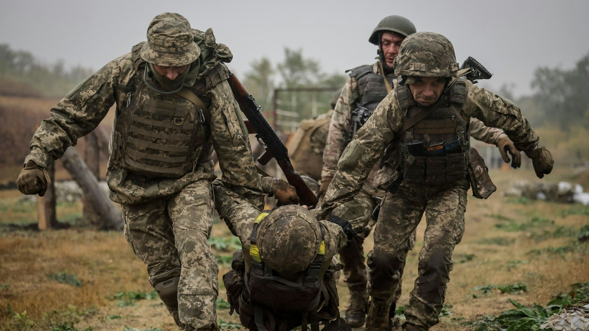 Soldaten tragen einen anderen Soldaten weg.