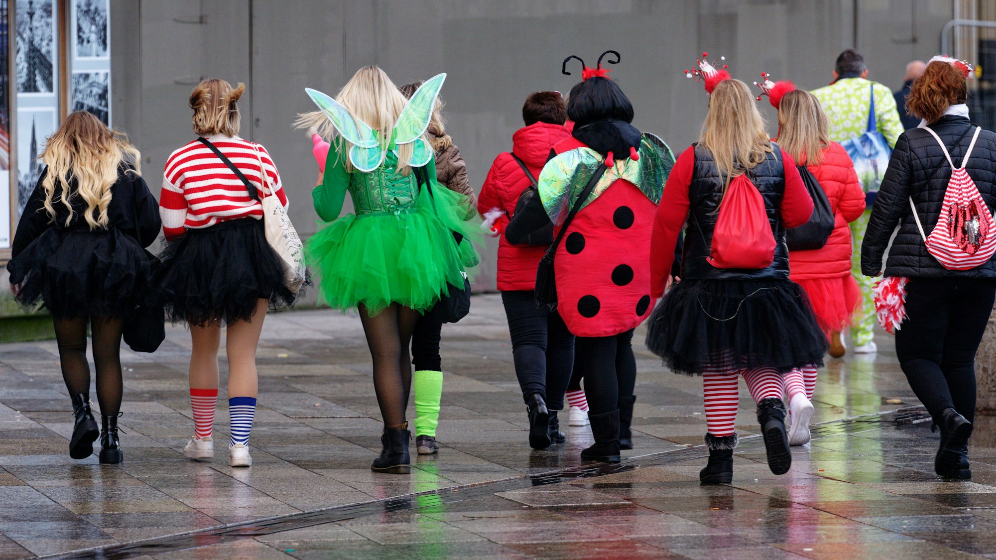 Eine Gruppe von Frauen läuft in Kostümen an Karneval über die Domplatte.
