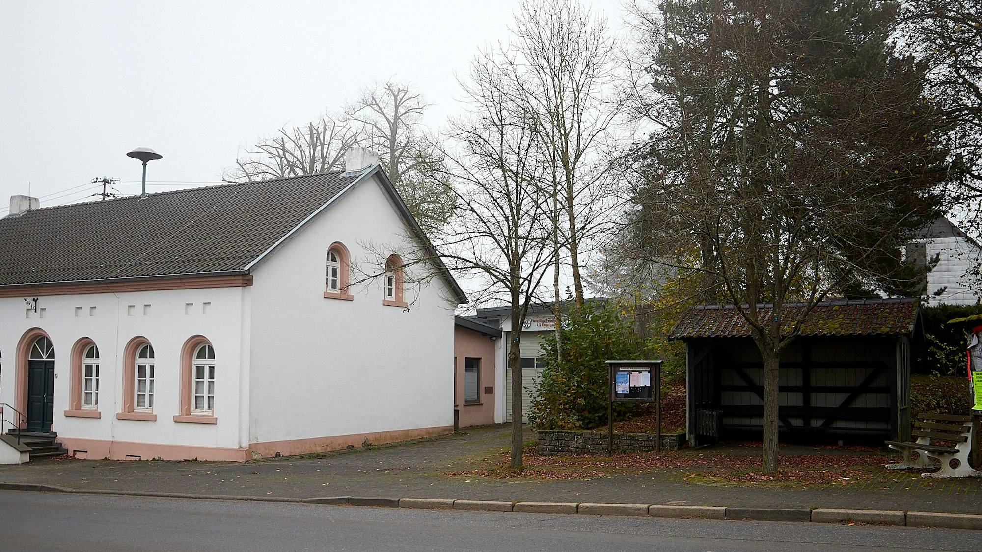 Neben einem Haus steht eine Bushaltestelle.