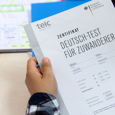 Eine Kursteilnehmerin freut sich über ihr Zertifikat „Deutsch-Test für Zuwanderer“, das sie für die erfolgreiche Teilnahme an einem Integrationskurs für Zuwandererbekommen hat.