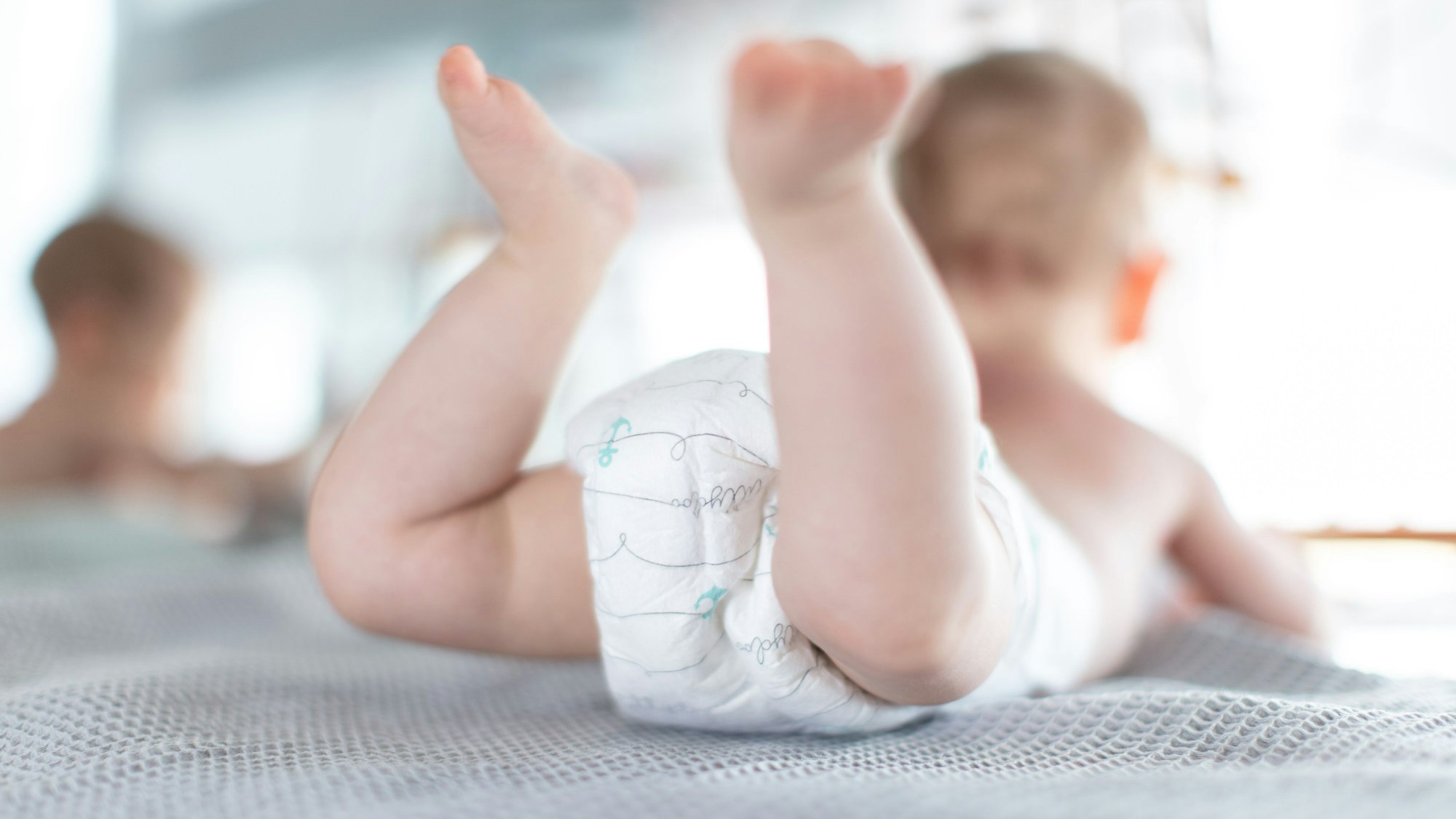 Ein Säugling trägt eine Windel, während er auf einer Kommode liegt.